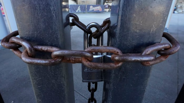 Locked gates are shown at Truist Park, home of the Atlanta Braves baseball team, Wednesday, March 2, 2022, in Atlanta. With owners and players unable to agree on a labor contract to replace the collective bargaining agreement that expired Dec. 1, baseball commissioner Rob Manfred followed through with his threat on Tuesday and canceled the first two series for each of the 30 major league teams. (AP Photo/John Bazemore)